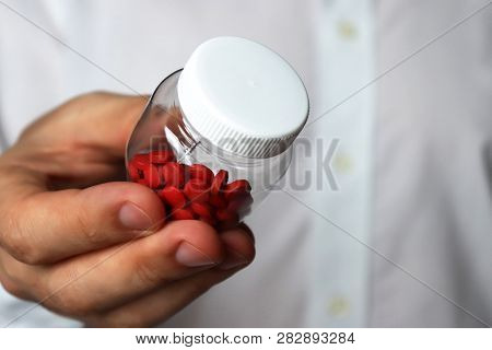 Doctor With Pills, Man In White Lab Coat Giving Bottle With Red Tablets. Concept Of Hospital, Dose O