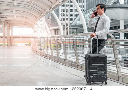 Young Business Man Man On Business Trip Standing With His Luggage And Making A Call Outside Airport.