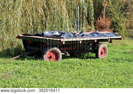 Rustic Old Vintage Colorful Wooden Tractor Trailer Covered With Thick Black Nylon Protection Left In