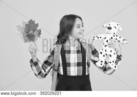 Nourish Child With Game. Small Child Hold Toy Doll And Autumn Leaves. Little Girl Play Game In Schoo