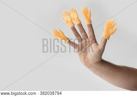 Hand On A White Background On Her Fingers Is Wearing A Toy In The Shape Of A Hand. Concept. No Choic