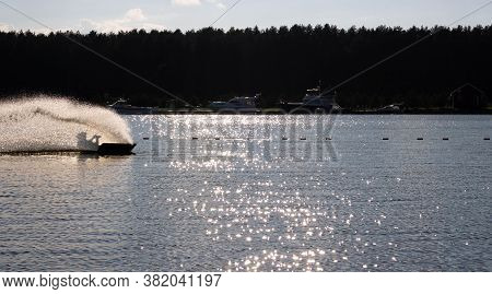 Waterskier Silhouette Moving Fast In Splashes Of Water At Sunset.