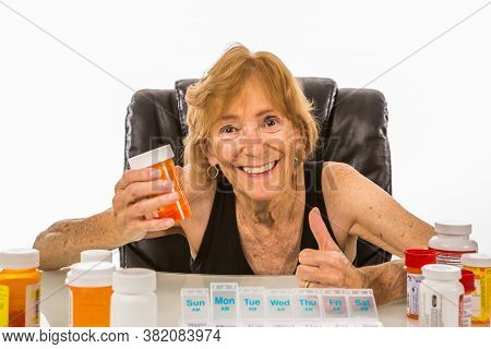 Senior Woman Smiling & Putting Thumbs Up On Medication To Be Included In Her Weekly Pill Dispenser