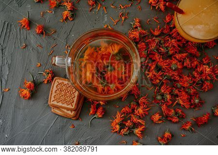 Tea With Calendula Flowers And Biscuits. Transparent Glass Cup And Saucer