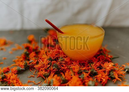 A Small Cup Is Filled To The Top With Yellow Liquid Honey, Orange Calendula.