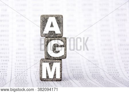 Three Stone Cubes On The Background Of White Financial Statements, Tables With The Word Agm Annual G