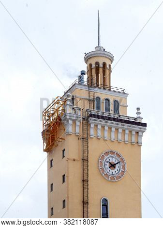 Beige Clock Tower, Spire, Small Windows And A Thin Long Staircase, Against The Sky