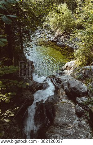 Close Up Rindbach Waterfall From Wooden Bridge With Forest And Small Lake. Austria Alps Mountain
