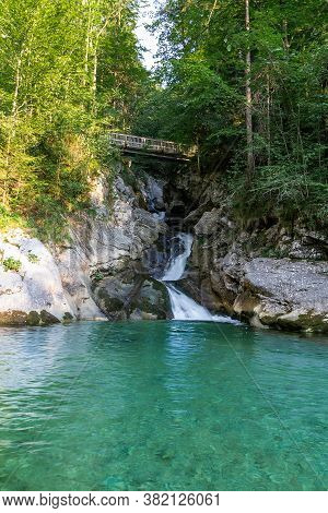 Rindbach Waterfall With Wooden Bridge And Forest. Austria Alps Mountain