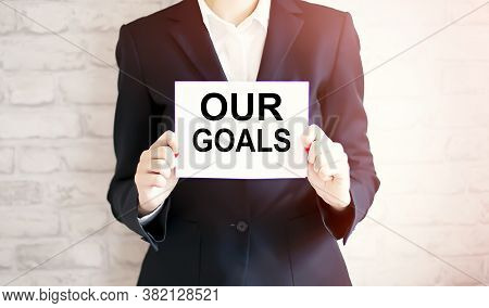 Woman Showing White Card With Our Goals Word . Business Concept