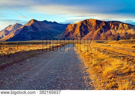 Orange sunset of the Southern hemisphere. Los Glaciares is Argentina's most beautiful natural park. Dirt rocky road. The concept of active, extreme and photo touris