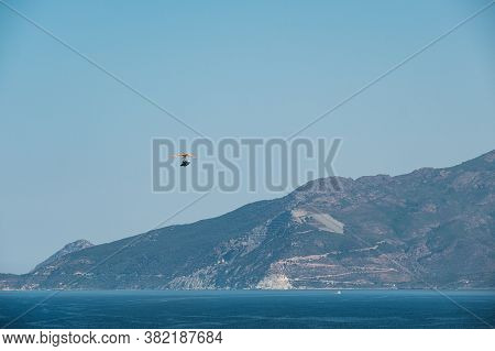 A Flying Boat Soars Above The Bay Saint Florent In Corsica With The Ancient Asbestos Mine On Cap Cor