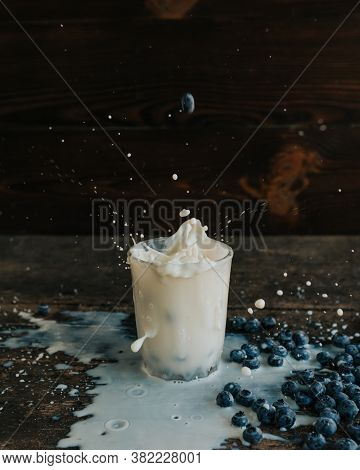 Berries Are Thrown Into The Transparent Glass Making Splashes Of Milk