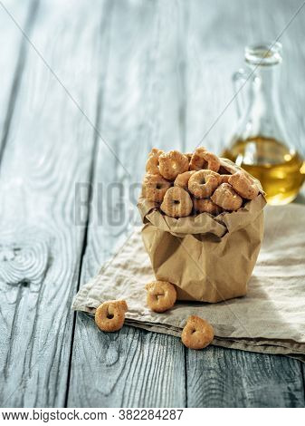 Traditional Italian Snack Taralli Or Tarallini In Paper Bag Over Old Gray Wooden Table. Rustic Shot 