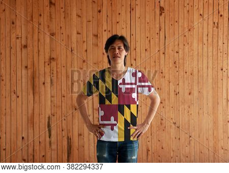 Man Wearing Maryland Flag Color Shirt And Standing With Akimbo On The Wooden Wall Background, The St