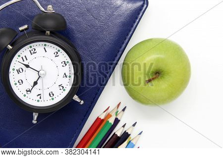 Back To School. Educational Concept, Office Supplies. Blue Book, Green Apple, Alarm Clock And Colore