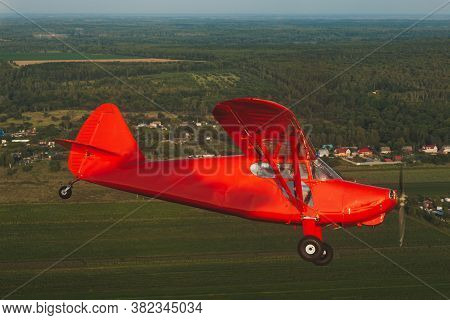 Vintage Red Small Plane Stinson In Flight Over The Green Forest.