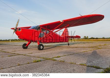 A Vintage Red Small Plane Stinson Is Preparing To Take Off On A Private Concrete Runway.