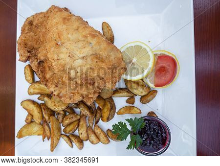 Feldkirch, Austria - July 26, 2020: Breaded Cordon Bleu Steak Served With Baked Potatoes, Cranberry 