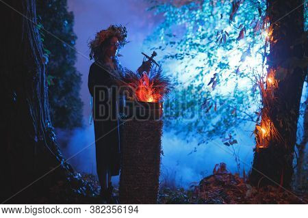 A Forest Witch Brews A Potion Holding A Voodoo Doll.