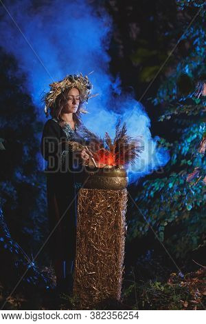 A Forest Witch Brews A Potion Holding A Voodoo Doll.