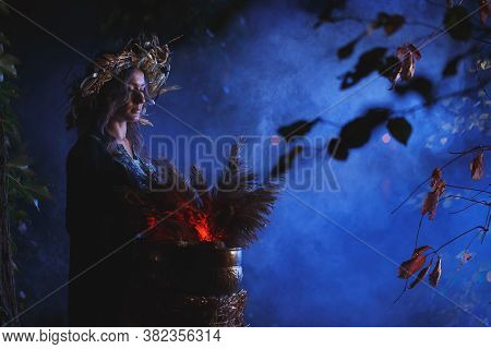 A Forest Witch Brews A Potion Holding A Voodoo Doll.