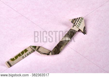 One Hundred Dollar Bill Arrow Origami. Arrow Made Of Banknote Isolated On Pink Nackground. Currency 