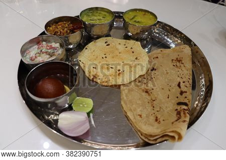North Indian Thali Consisting Of Multiple Bowls Full Of Curries, And Dessert With Salad. Indian Food