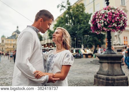 Loving Couple Walking In Old Lviv City Wearing Traditional National Ukrainian Shirts. Newlyweds Spen