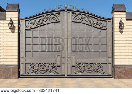Wrought Iron Gates With Ornament. Facade Of The House.