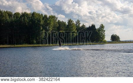 Waterskier Silhouette Moving Fast In Splashes Of Water At Sunset.