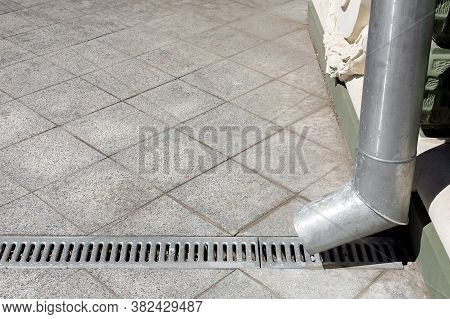 An Engineering Structure A Downspout With A Drainage Grate Against A Background Of A Gray Stone Gran