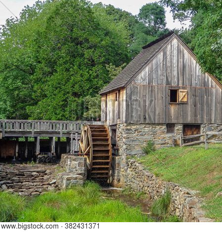 And Old Barn With A Water Wheel Sits By A Stream