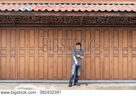 Asian Long Hair Man Is Standing And Posting In Front Of Classic Backdrop Wood Wall And Door In Front