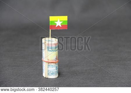 Rolled Banknote Money Ten Thousand Myanmar Kyats And Stick With Mini Myanmar Flag On Dark Grey Floor