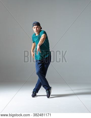Stylish Guy Breakdancer Dancing In Studio Isolated On Gray Background. Breakdance Lessons