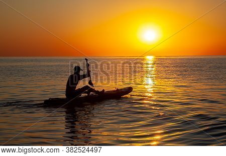 Silhouette Of A Man Floating On A Board With An Oar. Dawn Sun On The Sea. Swimming On A Supboard. Wa