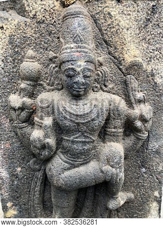 Hindu God Sculpture With Four Hands. Bas Relief Sculpture Carved In The Stone Wall Of Shiva Temple, 