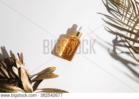White, Orange And Black Serum Bottles On White Background. Trending Golden Branches Of Palm And Prot