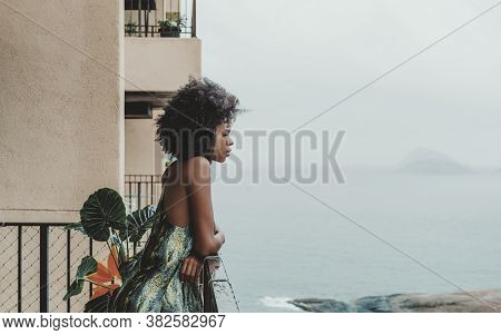 Side View Of A Sleepy Young African-american Female With Curly Afro Hair Leaning Against Wet Balcony