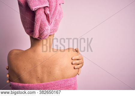 Middle age brunette woman wearing beauty black face mask over isolated pink background Hugging oneself happy and positive from backwards. Self love and self care