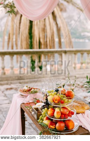 Whatnot For Fruit With Three Tiers With Apples, Grapes, And Pears On A Table In The Yard Near The Fe