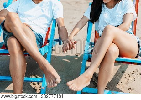Couple Sitting On The Deck Chairs At The Beach. Honymoon, Love, Travel Or Vacation Concept.