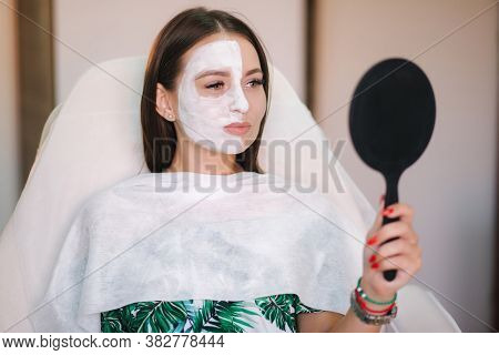 Beautiful Woman With White Mask On Hulf Of Face. Attractive Brunrtte Woman In Beauty Salon