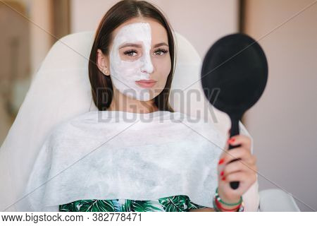 Beautiful Woman With White Mask On Hulf Of Face. Attractive Brunrtte Woman In Beauty Salon