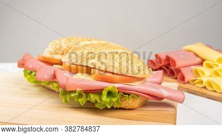 Mortadella Sandwich, Lettuce, Tomato And Cheese On A Polished Board And Slices Of Mortadella And Che