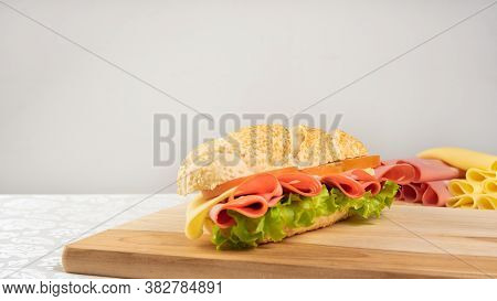 Mortadella Sandwich, Lettuce, Tomato And Cheese On A Polished Board And Slices Of Mortadella And Che