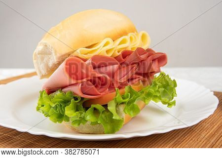 Mortadella Sandwich, Lettuce And Cheese On A White Plate And A Bamboo Mat With White Background On A
