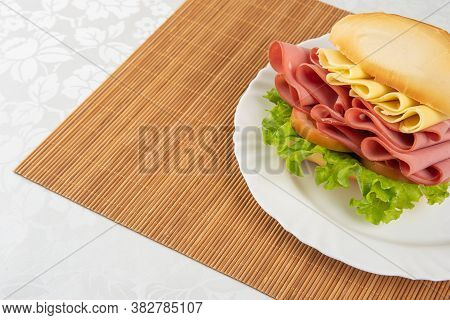 Mortadella Sandwich, Lettuce And Cheese On A White Plate And A Bamboo Mat With White Background On A