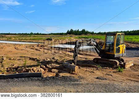 Mini Excavator Digg Trench To Lay Cables Concrete Curbs And Paving Slabs At Construction Site. Backh